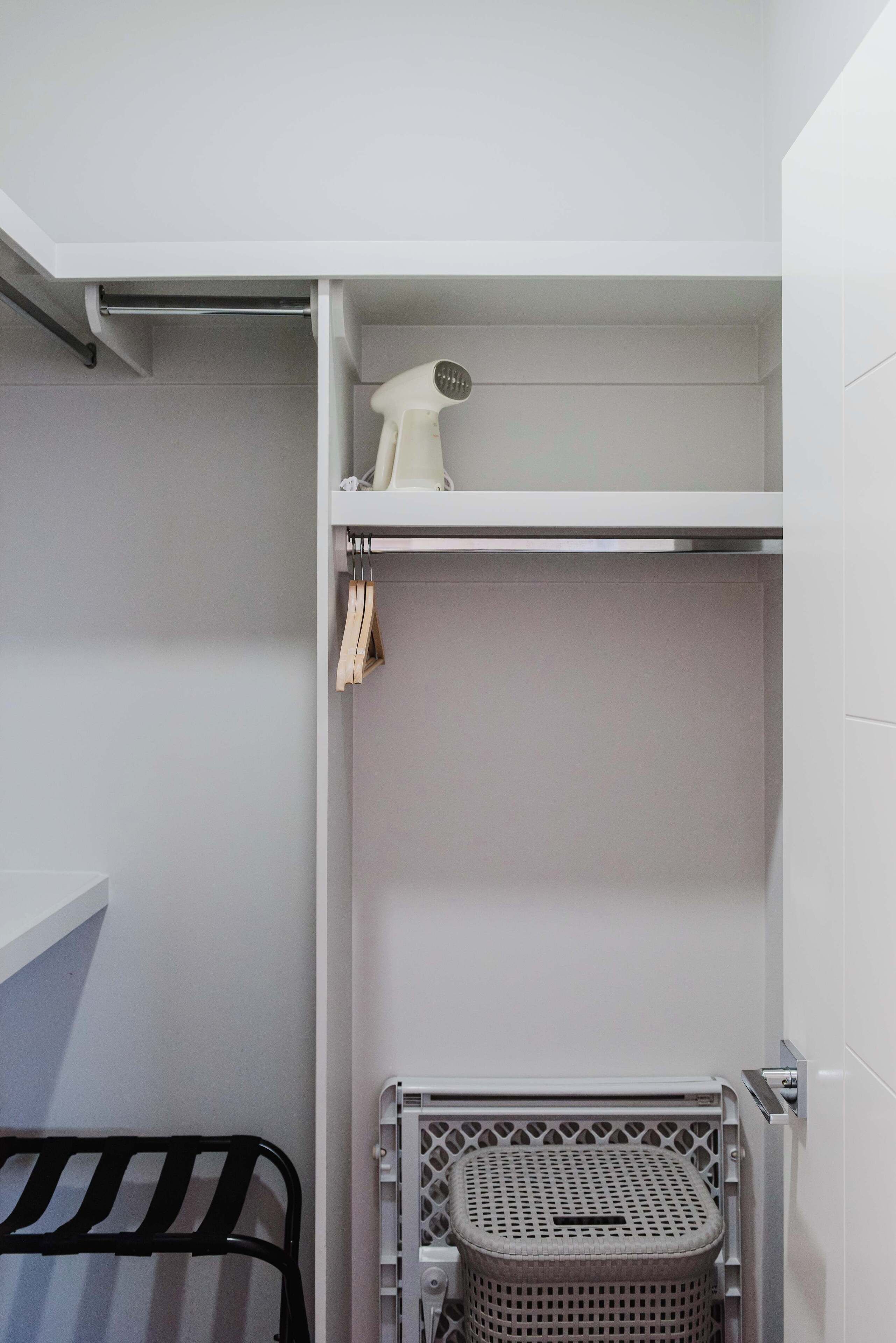 Un baño pequeño con lavamanos blanco, un tendedero y una cesta de ropa.