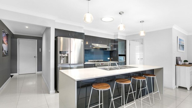 A modern kitchen with a central island, stainless steel appliances, and bar stools.
