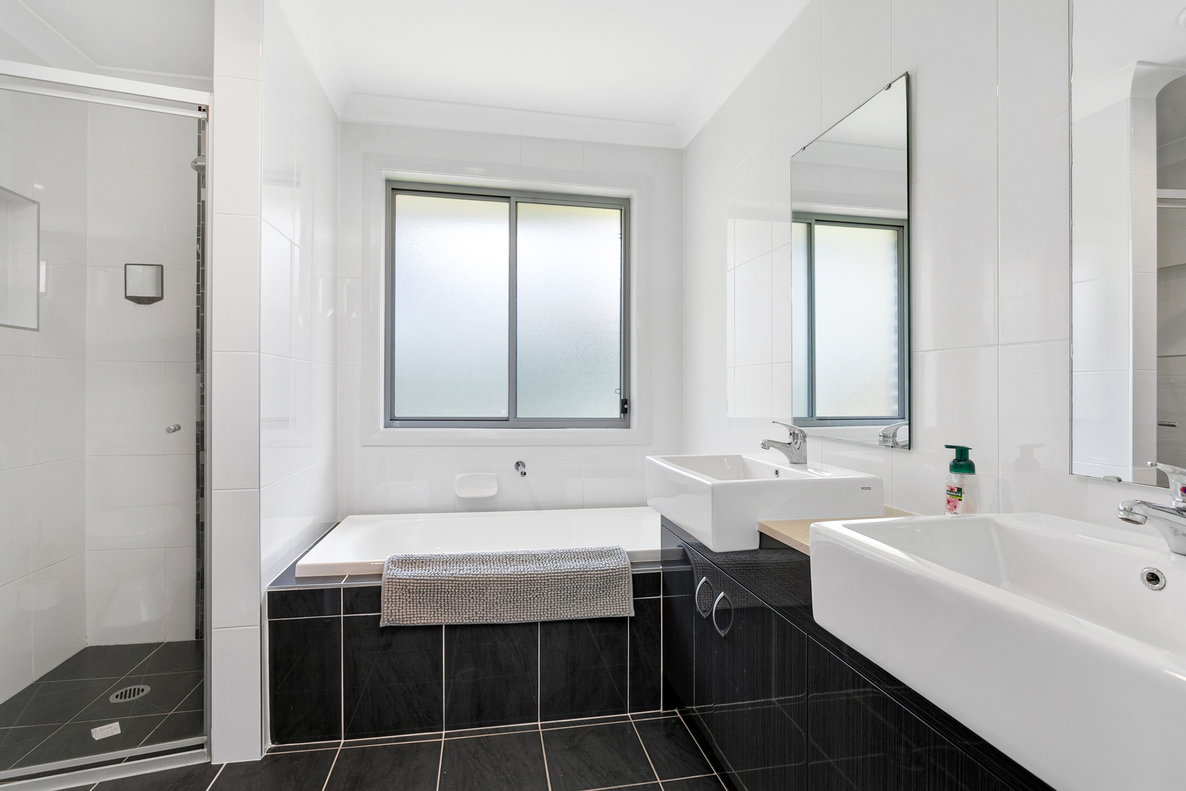 Un baño moderno con una bañera amplia, dos lavabos y una zona de ducha.