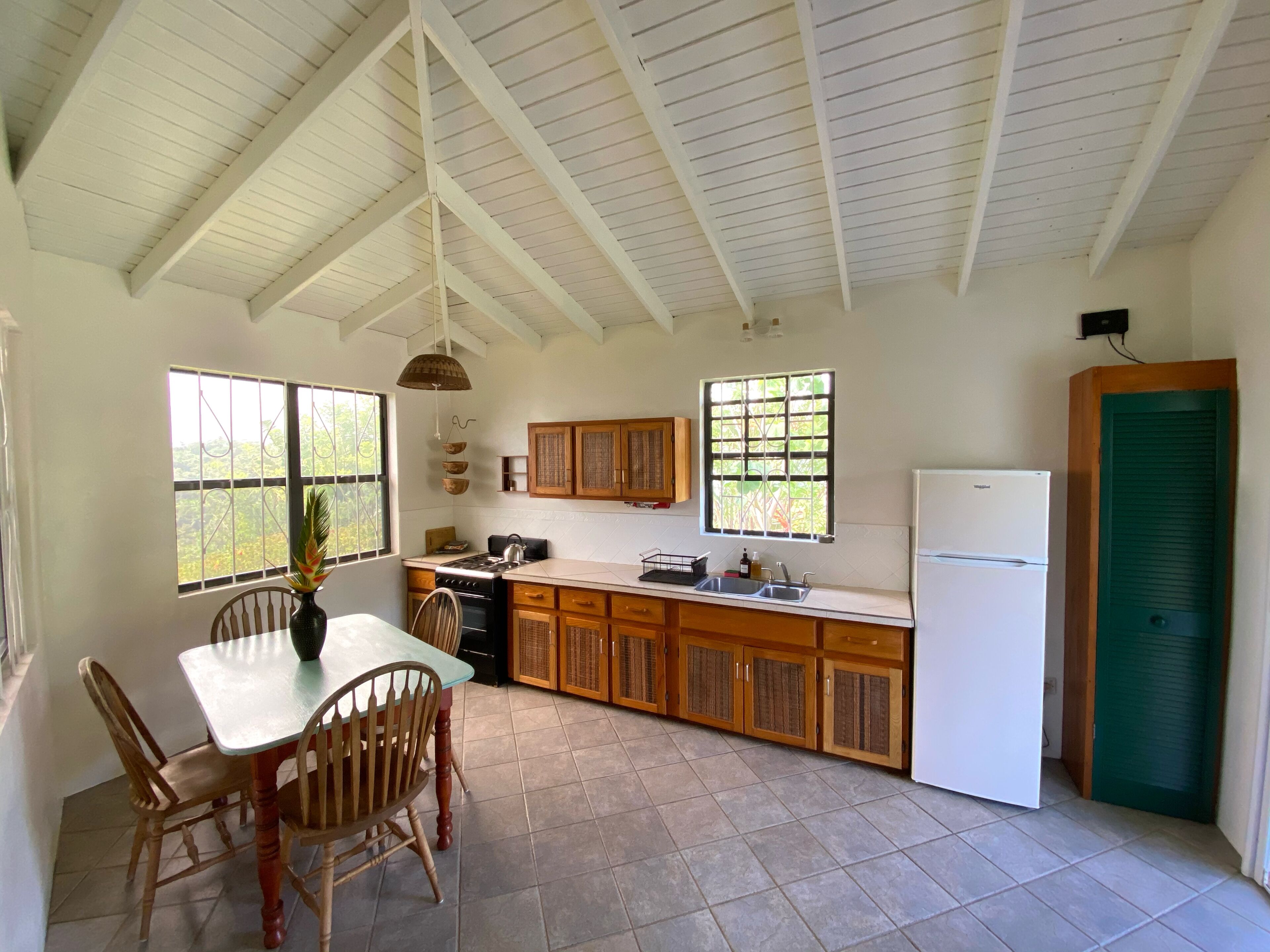 A kitchen with a dining table, chairs, a stove, cabinets, and a refrigerator.