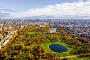 Vista aerea di una città con un grande parco che presenta un lago, circondato da edifici e vegetazione.