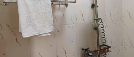Un baño con ducha, perchero y repisa.