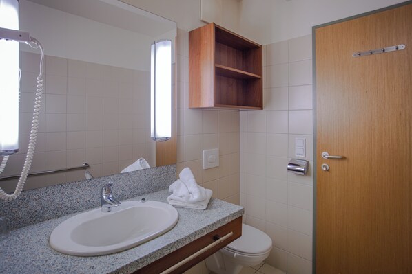 A bathroom with a granite countertop sink, a wooden medicine cabinet, a toilet, and a door with a handle. - Feriendorf am Maltschacher See (Feldkirchen in Kaernten)