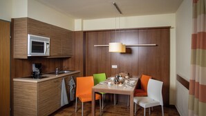 A compact kitchen with a microwave, sink, and a dining area with chairs and a table.