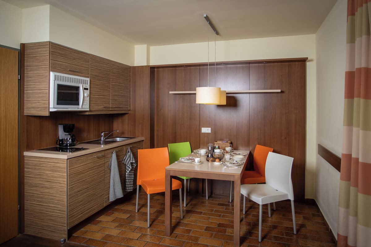 Une cuisine compacte équipée d’un four à micro-ondes, d’un évier et d’un coin repas avec des chaises et une table.