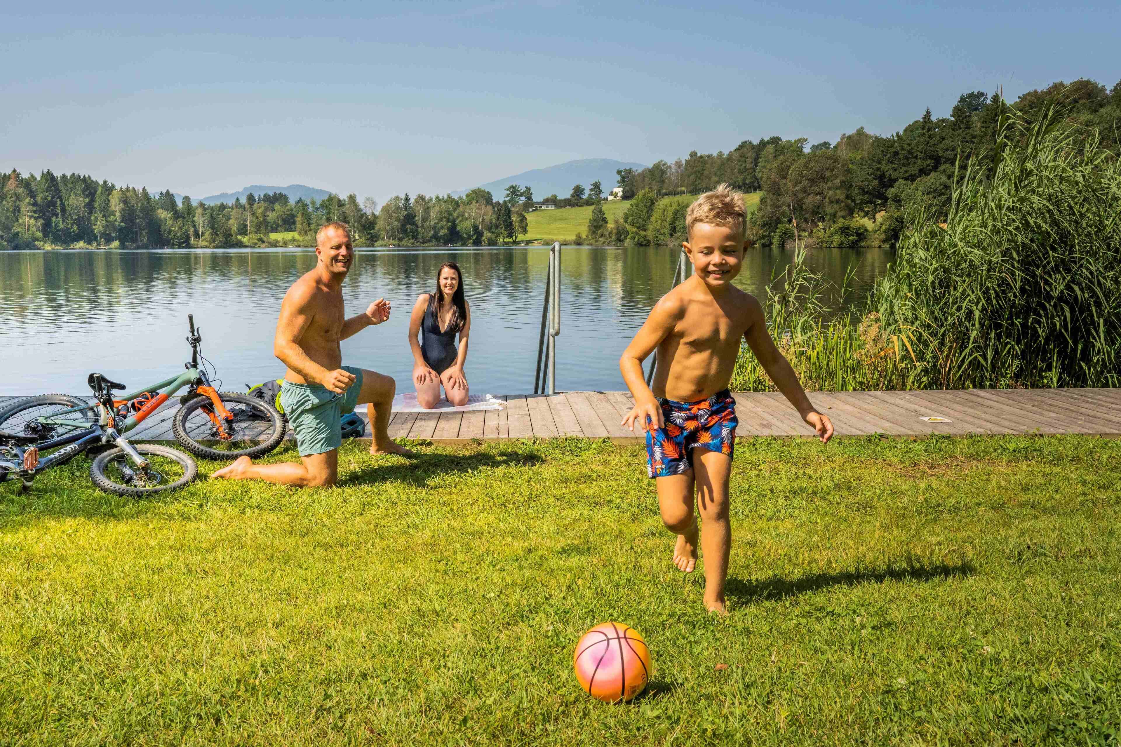 A lakeside setting with a grassy area, a bicycle, and a basketball.