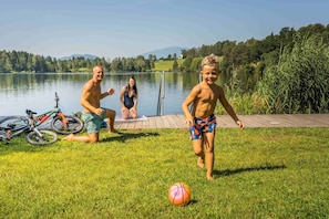 Um cenário à beira do lago com gramado, uma bicicleta e uma cesta de basquete.