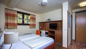 A hotel room with a bed, a desk, a television, and a door marked with the number 32.
