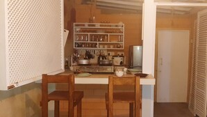 A compact kitchen with wooden chairs, a white countertop, and shelves with kitchenware. - Superb 2-bedroom villa in Mirissa (Mirissa)