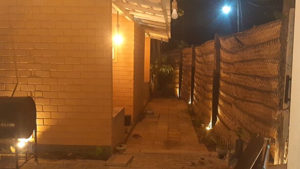 A narrow alleyway with brick walls, a metal fence, and a lit barbecue grill. - Superb 2-bedroom villa in Mirissa (Mirissa)