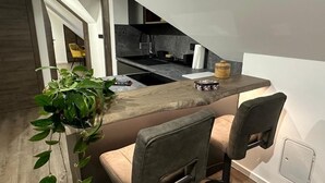 A modern kitchen with a wooden countertop, two bar stools, and a hanging plant. - 4 Elements Resort Bled Studio with sofa bed (Radovljica)
