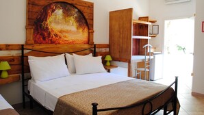 A bedroom with a bed, a wooden headboard, a painting, a desk, and a chair.
