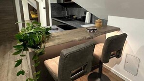 A modern kitchen with a wooden countertop, two chairs, and a potted plant. - 4 Elements Resort Bled Studio Standard (Radovljica)