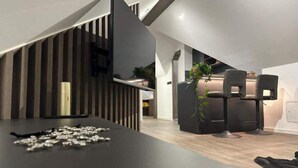 A modern kitchen with a black countertop, a built-in stove, and a wooden accent wall. - 4 Elements Resort Bled Studio Standard (Radovljica)
