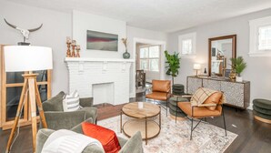 A modern living room with a fireplace, comfortable seating, and a large mirror. - StayDelta | Hyde Park (Cincinnati)