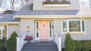 A two-story house with a light gray exterior, a pink front door, and a number "1130" on the front wall. - StayDelta | Hyde Park (Cincinnati)