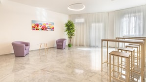 A spacious room with a marble floor, two purple chairs, a small table, a potted plant, and a colorful painting on the wall. - Krono Relais - Camera Matrimoniale (Gallipoli)