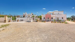 A building with a white facade, a red and white striped awning, and a gravel courtyard.