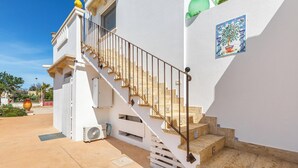 A white building with a staircase leading to a balcony.