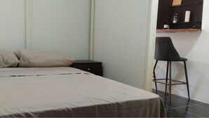 Un dormitorio con una cama, dos almohadas, una mesita de noche y una silla.