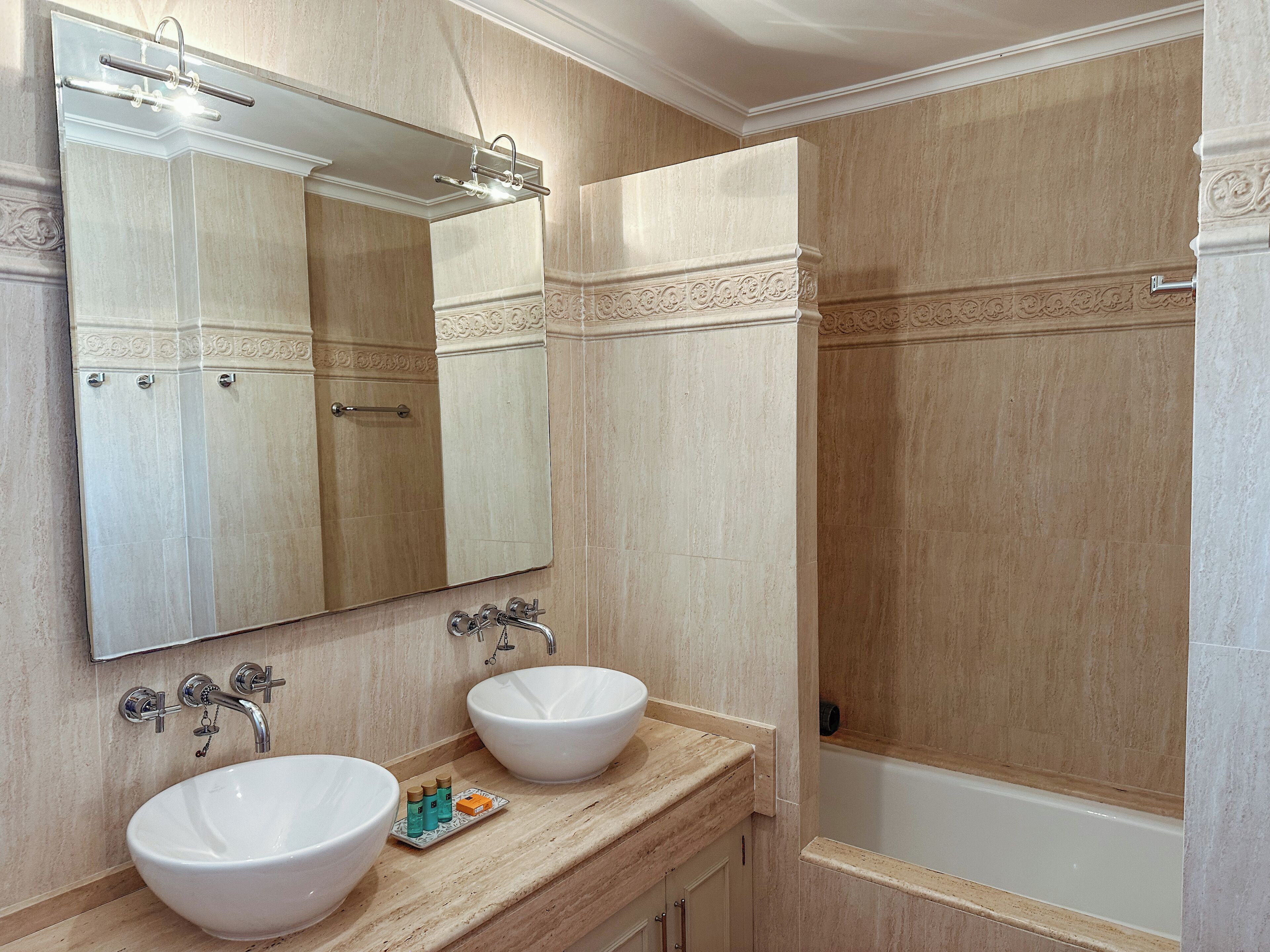 A bathroom with two sinks, a large mirror, and a bathtub.