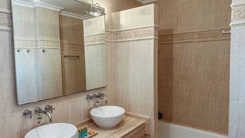 A bathroom with two sinks, a large mirror, and a bathtub.