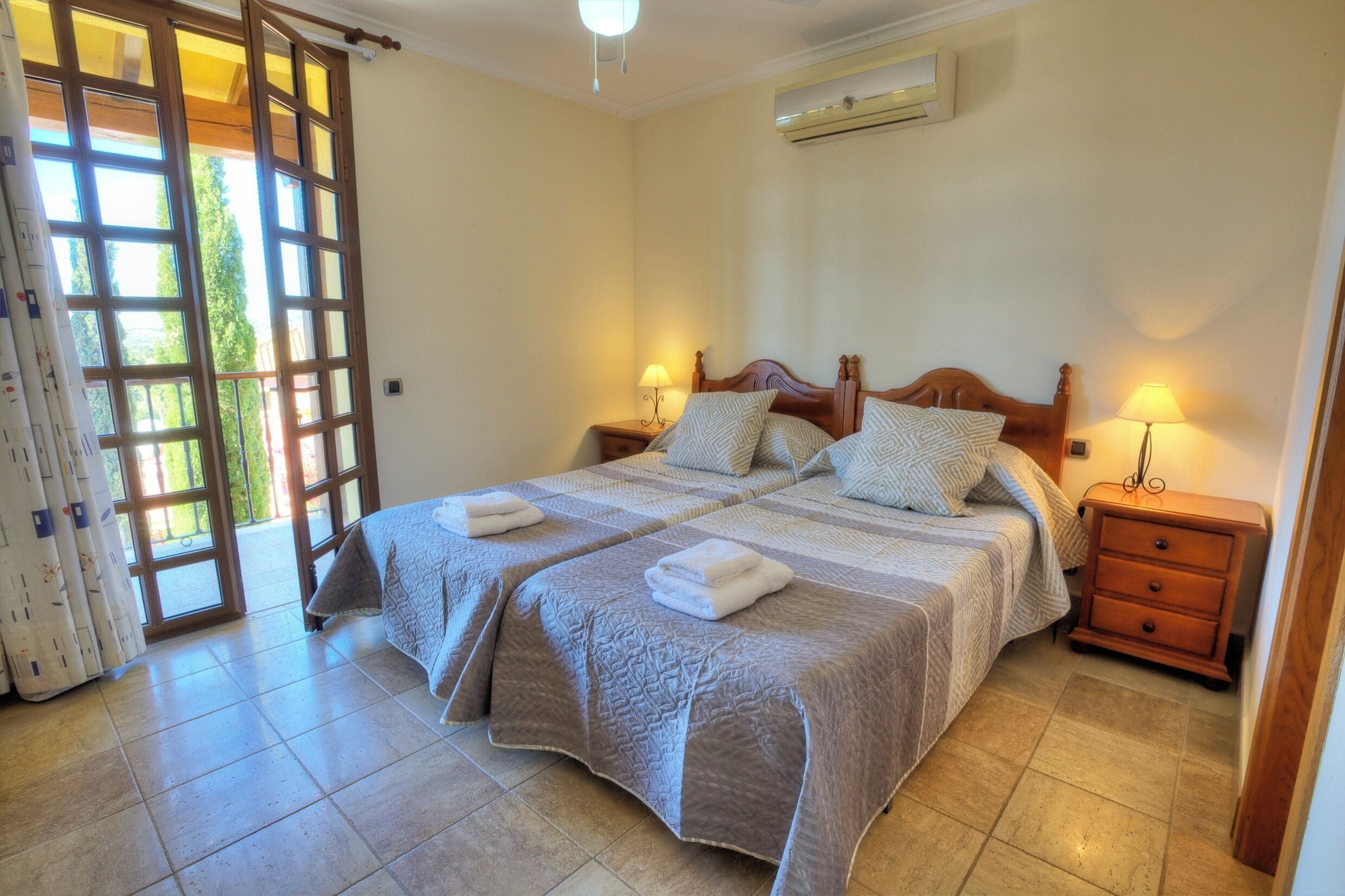A double bed with two pillows, a nightstand, and a lamp.