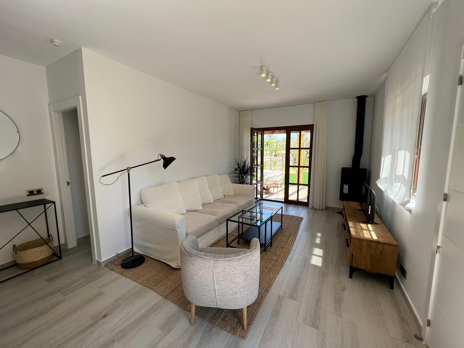 A modern living room with a sofa, coffee table, floor lamp, and a TV stand.