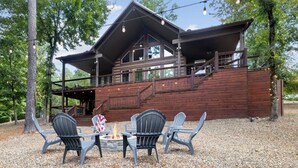 Eine zweistöckige Holzhütte mit Terrasse und Sitzgelegenheit im Freien.