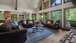 Ein großzügiges Wohnzimmer mit Ledersofas, einem Couchtisch und großen Fenstern mit Blick ins Freie.