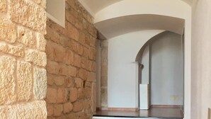 Ein Korridor mit Steinwänden, Fliesenboden und einer Treppe, die zu einer oberen Ebene führt.