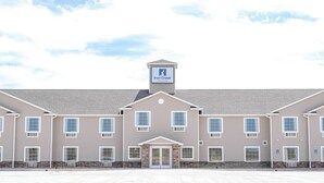 A multi-story hotel with a symmetrical facade, a central entrance, and a sign indicating it is an Iron Creek Inn & Suites. - Iron Creek Inn & Suites (Upton)