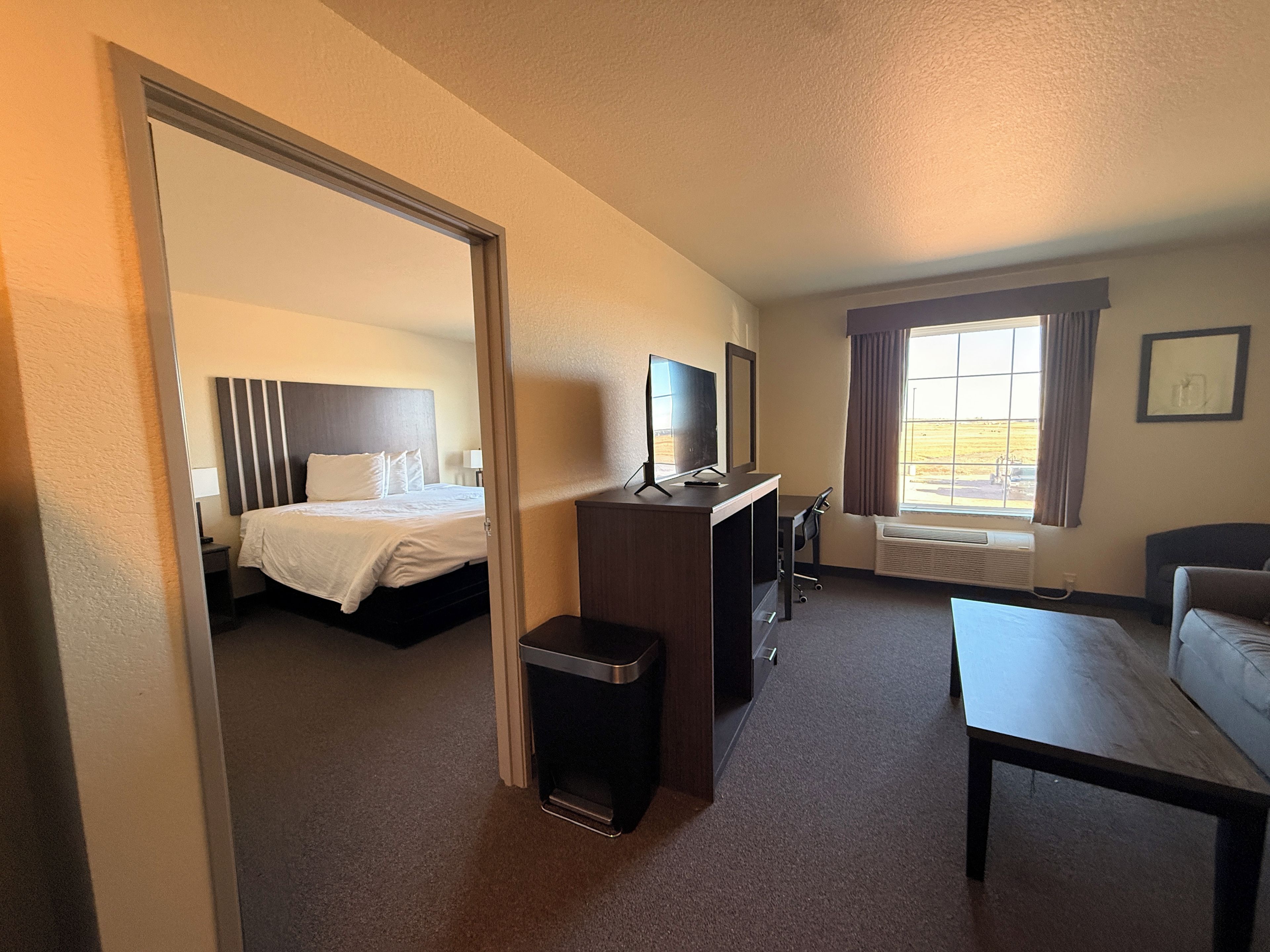 A hotel room with a bed, desk, chair, and a small table.