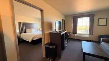 A hotel room with a bed, desk, chair, and a small table.