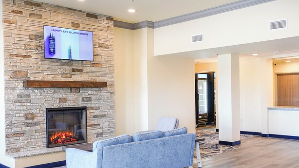 A modern lobby with a stone fireplace, a flat-screen TV, and a blue sofa. - Iron Creek Inn & Suites (Upton)