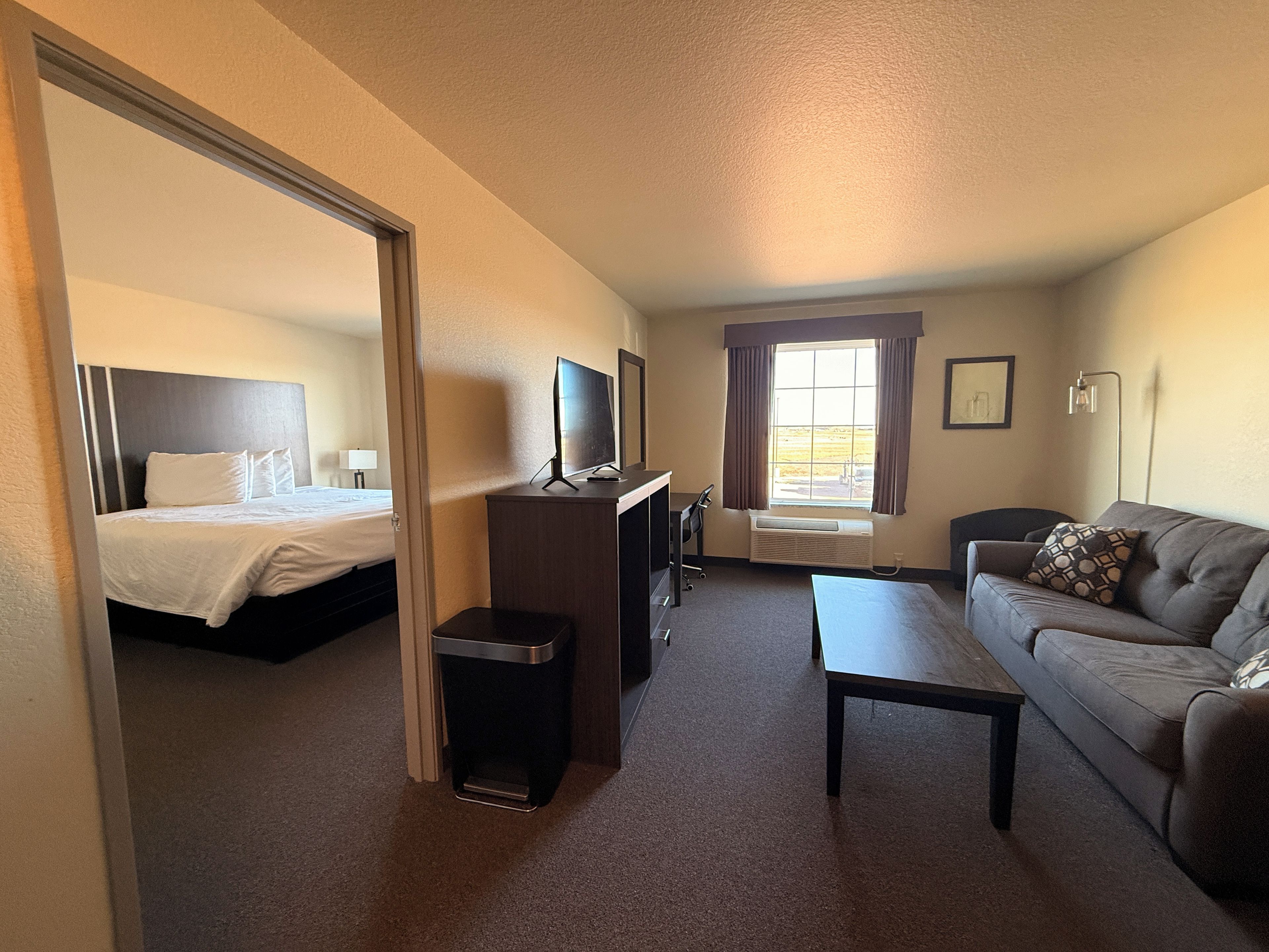 Une chambre d’hôtel avec un lit, un bureau, un canapé et une fenêtre avec des rideaux.
