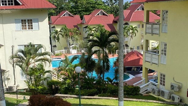 Un resort con varias edificaciones, una piscina y céspedes bien cuidados.