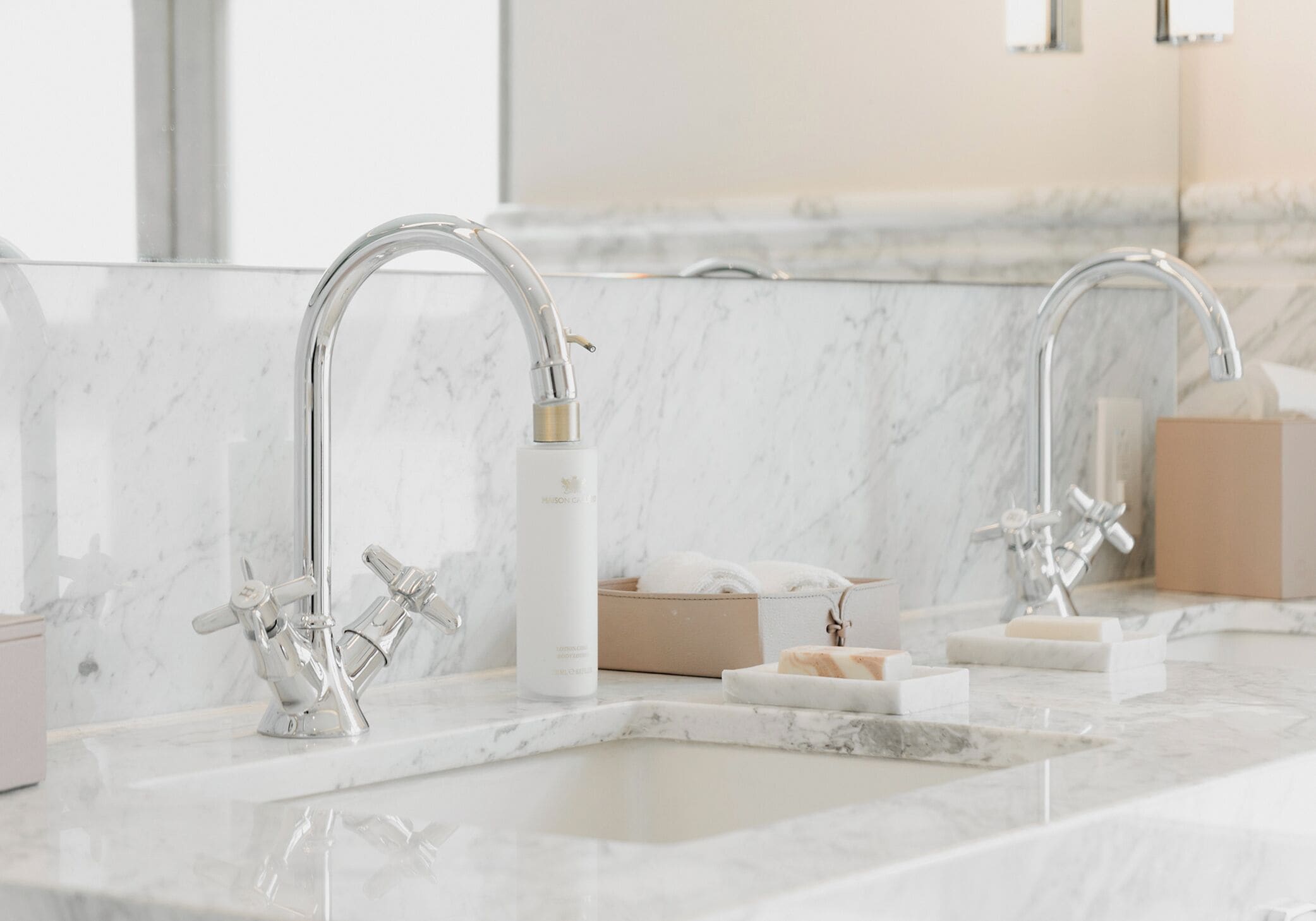 Une salle de bain moderne avec un plan de toilette en marbre, un robinet chromé et un miroir qui reflète la zone du lavabo.