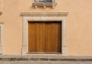 Une grande porte en bois, encadrée de pierre, intégrée à un bâtiment dont le mur est d’une grande simplicité.