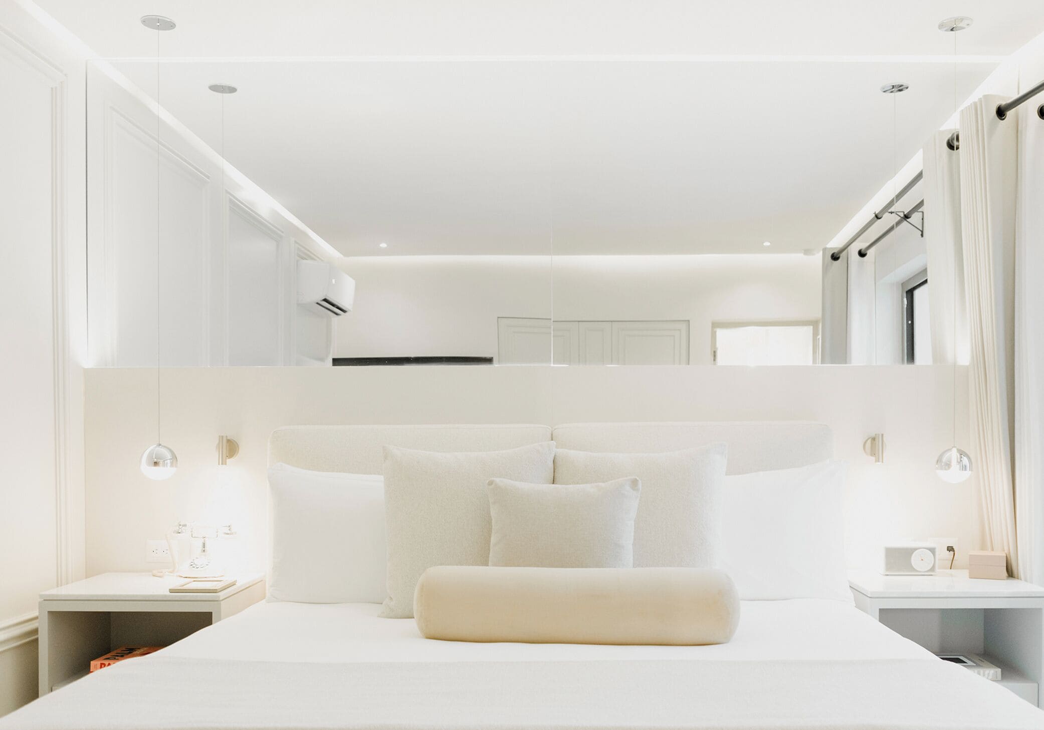 A modern bedroom with a large bed, bedside tables, and a built-in wardrobe.