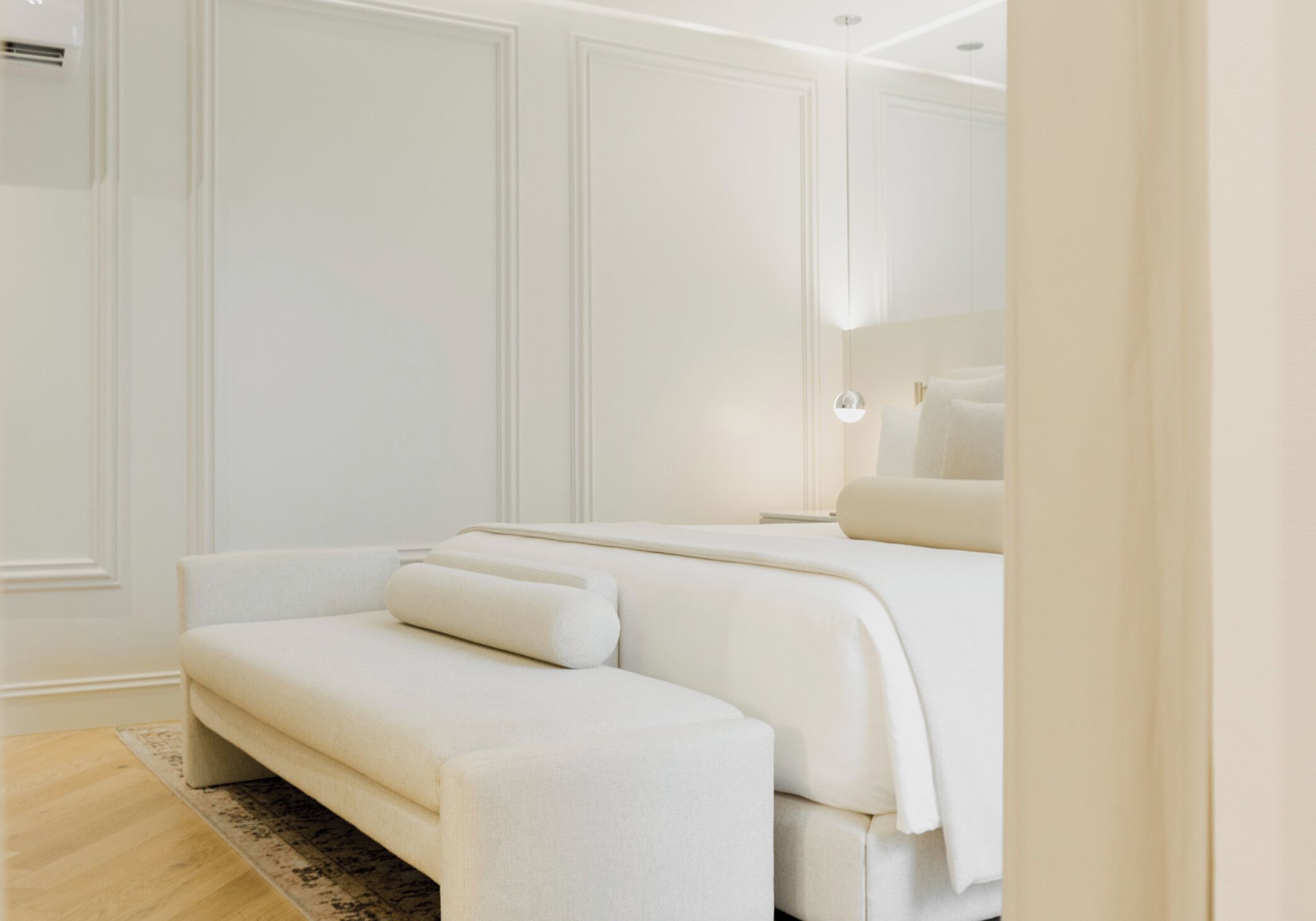 Une chambre à coucher moderne avec un grand lit, un banc et un miroir.