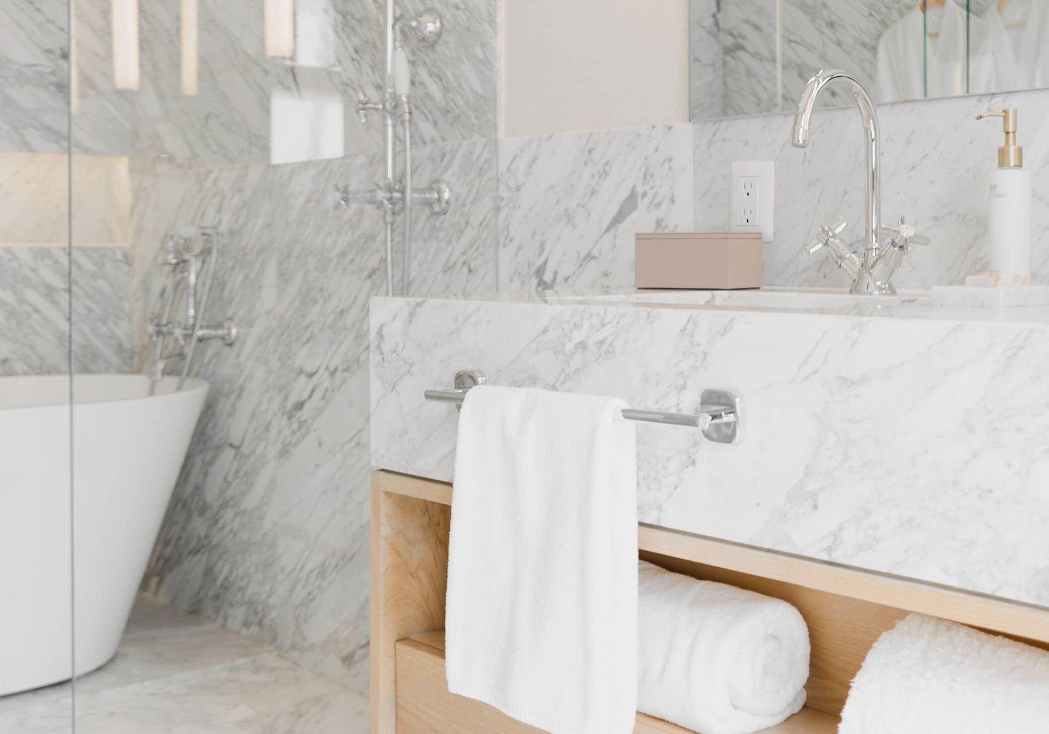 A modern bathroom with a freestanding bathtub, a marble countertop, and a towel rack.