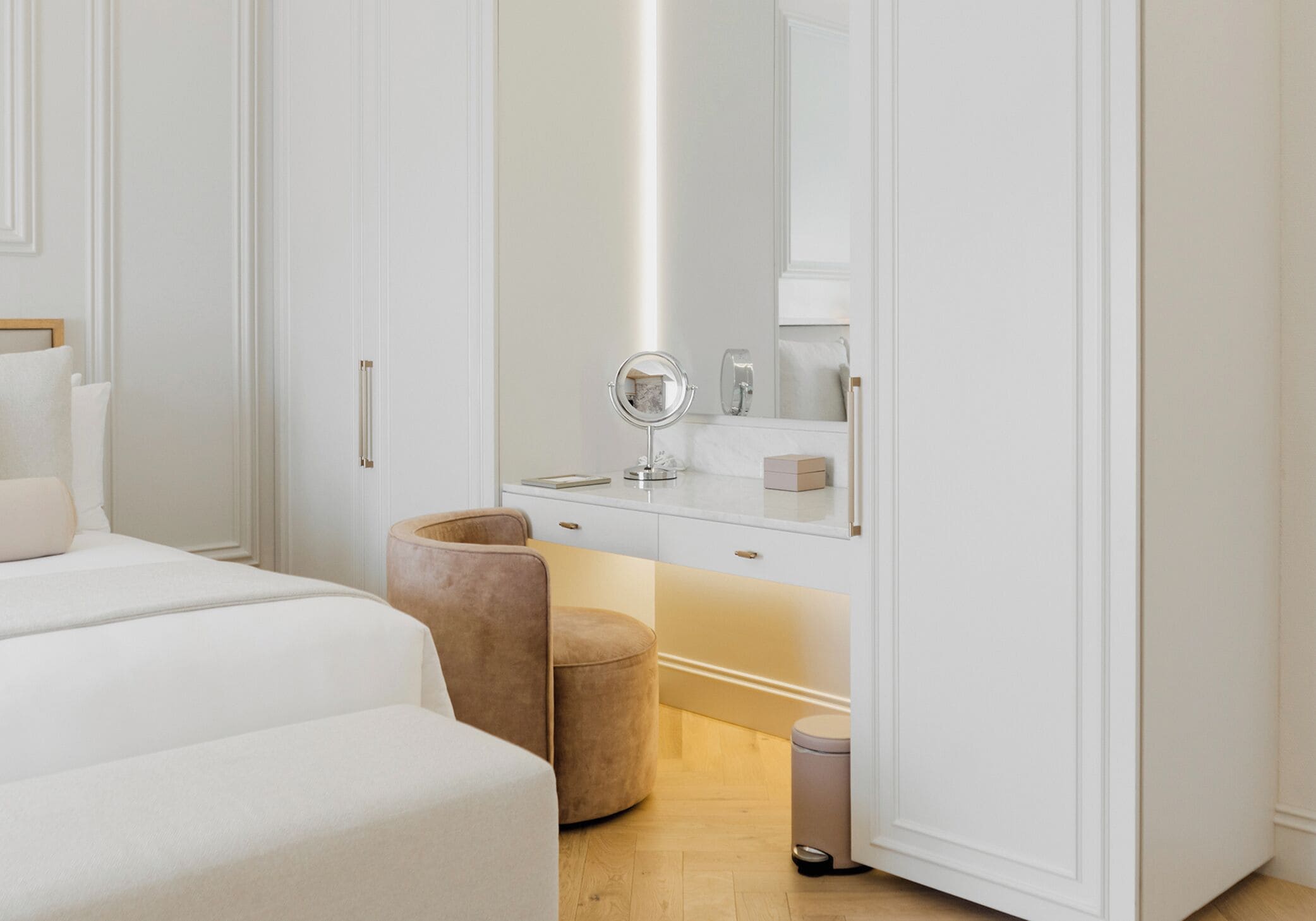 Een slaapkamer met een bed, een kaptafel met spiegel en een prullenbak.