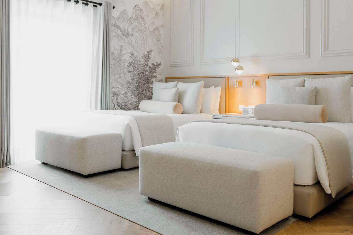 Een moderne hotelkamer met een groot bed, twee kleinere bedden en een zithoek.