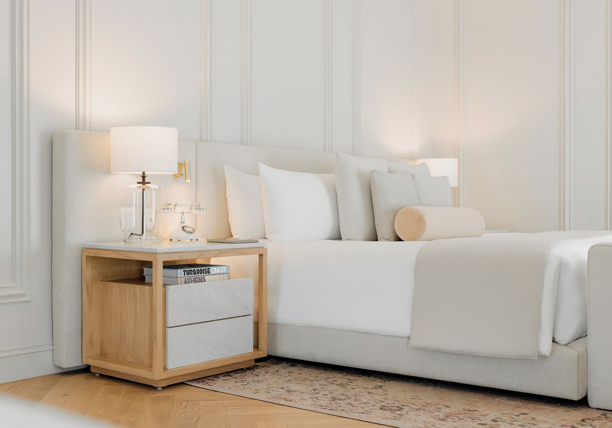 A neatly arranged bedroom with a bed, bedside tables, and a nightstand.