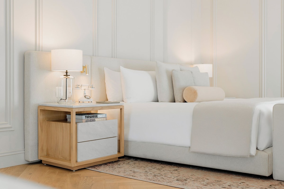 Un dormitorio ordenado con cama, mesitas de noche y un velador.