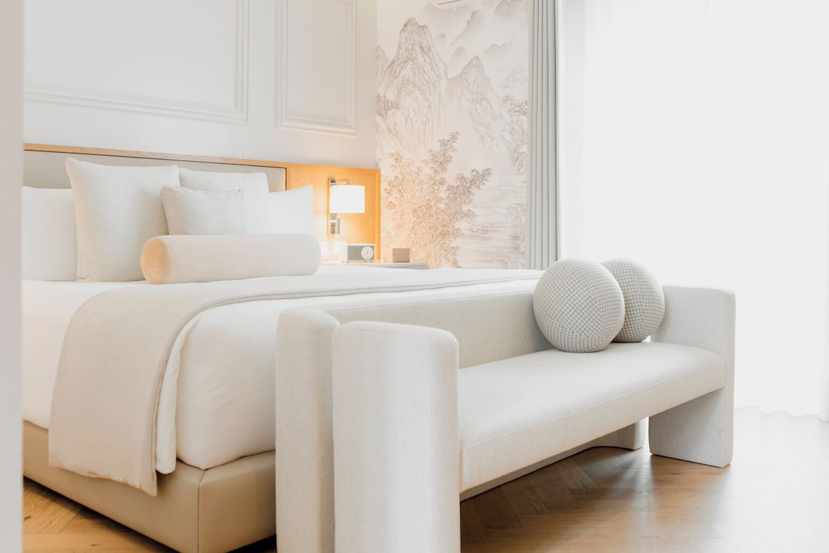 Un dormitorio moderno con cama, mesita de noche, lámpara y una pared con diseño de montaña.