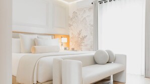Quarto moderno com uma cama grande, mesa de cabeceira com abajur e vista para uma paisagem montanhosa pela janela.