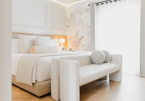 Un dormitorio moderno con una cama grande, una mesita de noche con lámpara, y vistas a un paisaje montañoso por la ventana.