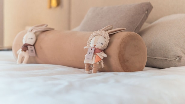 Uma cama com dois coelhinhos de pelúcia e uma etiqueta em um deles.